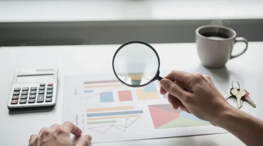 Analyse détaillée d'un dossier de prêt immobilier dans un bureau lumineux avec calculatrice et documents financiers