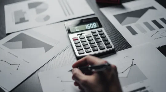 Bureau moderne avec documents financiers et calculatrice sous lumière dramatique